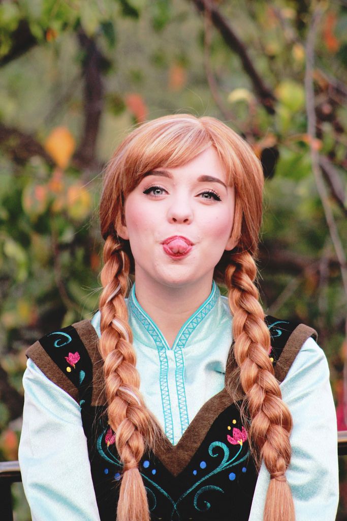 a woman with long red hair and braids making a funny face while sitting on a bench