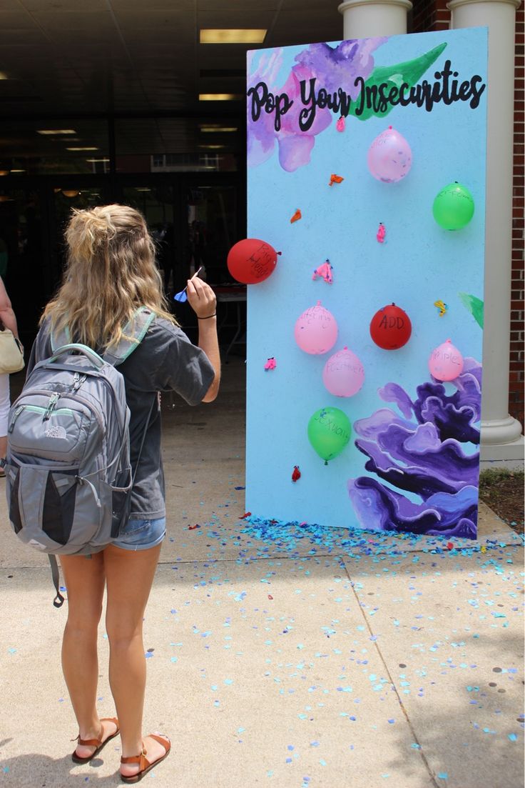 a woman standing in front of a sign with balloons on it