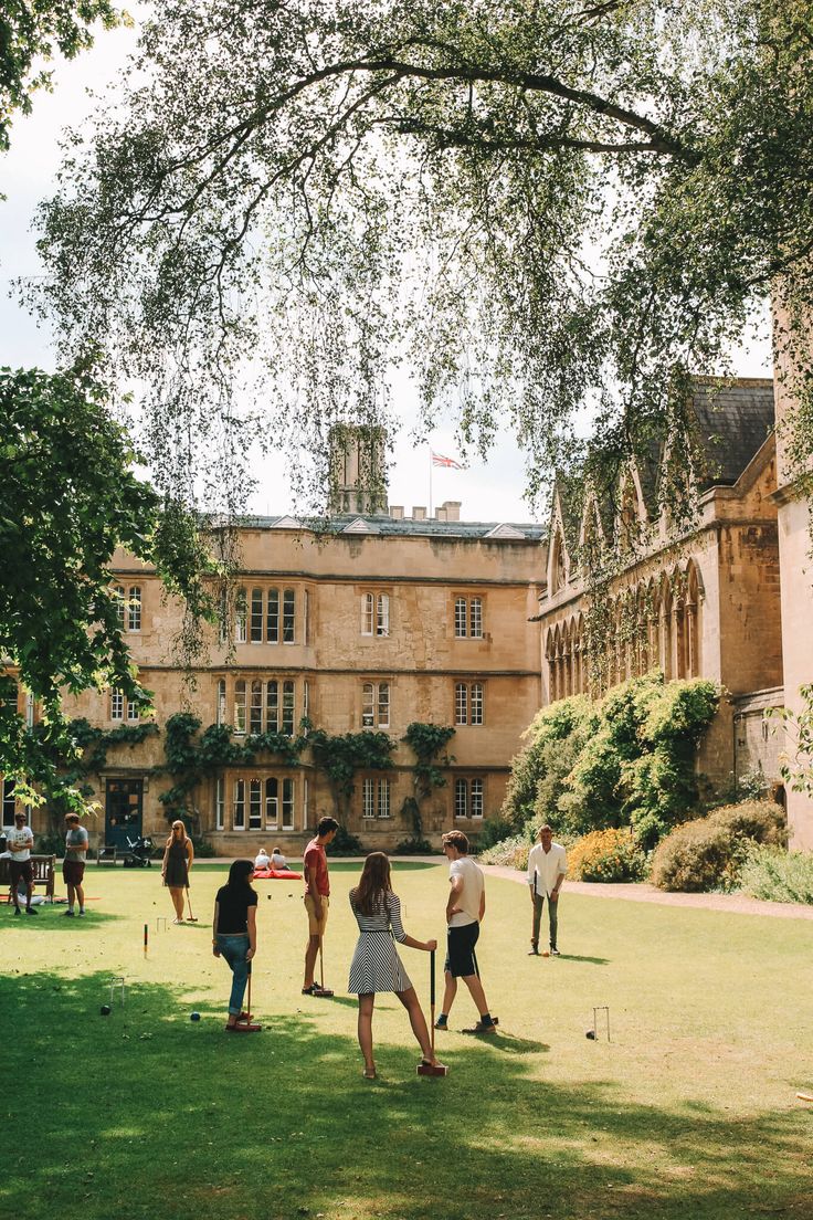 several people are playing croquet on the lawn in front of an old building