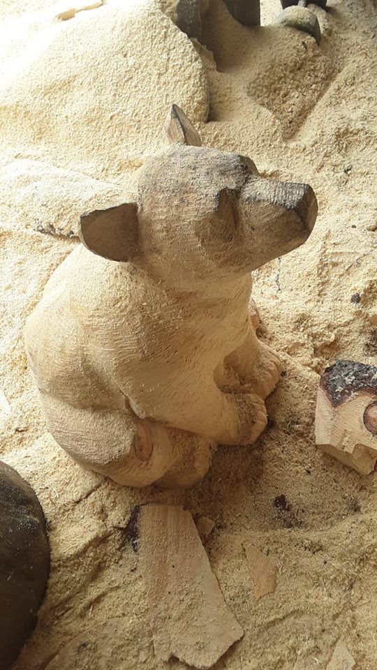 an animal statue sitting on top of a sandy ground