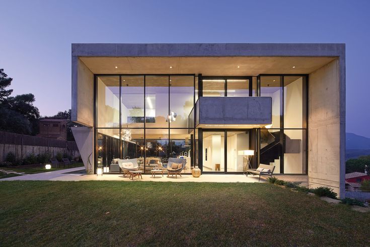 the house is lit up at night and has large windows on each side that allow natural light to enter