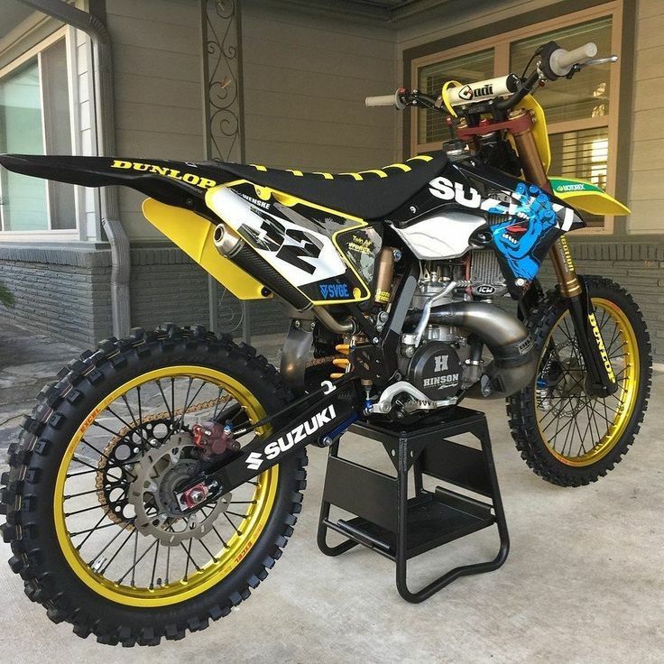 a yellow and black dirt bike parked in front of a building with two tires on it