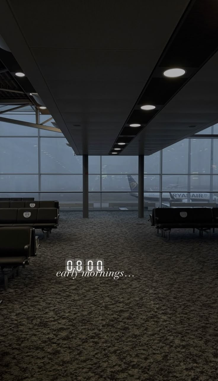 an empty airport terminal with benches and tables on the ground in front of large windows