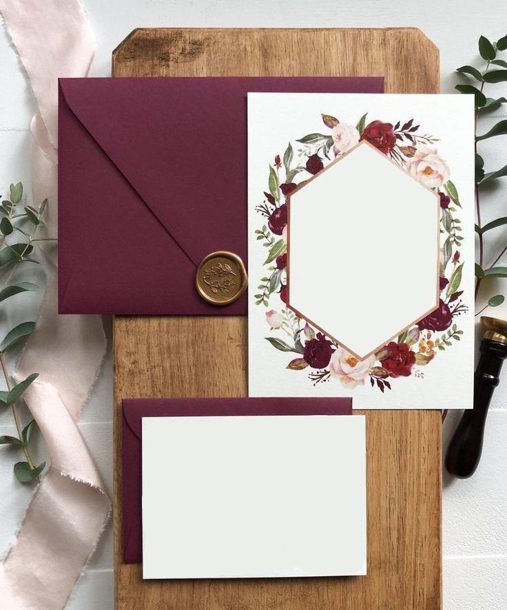 the wedding stationery is decorated with burgundy and white flowers