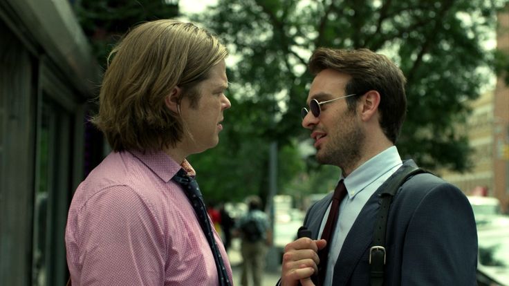 two men standing next to each other on the street with words written in front of them