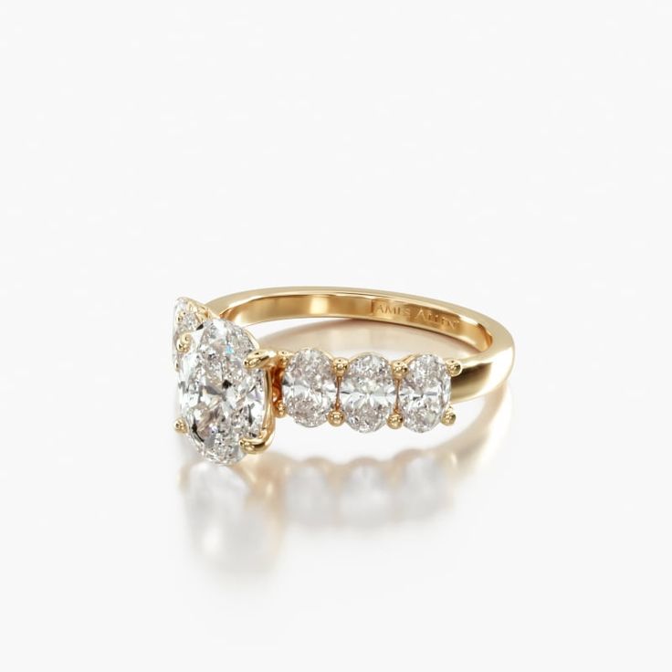 a yellow gold ring with three diamonds on the side and an oval shaped diamond in the middle