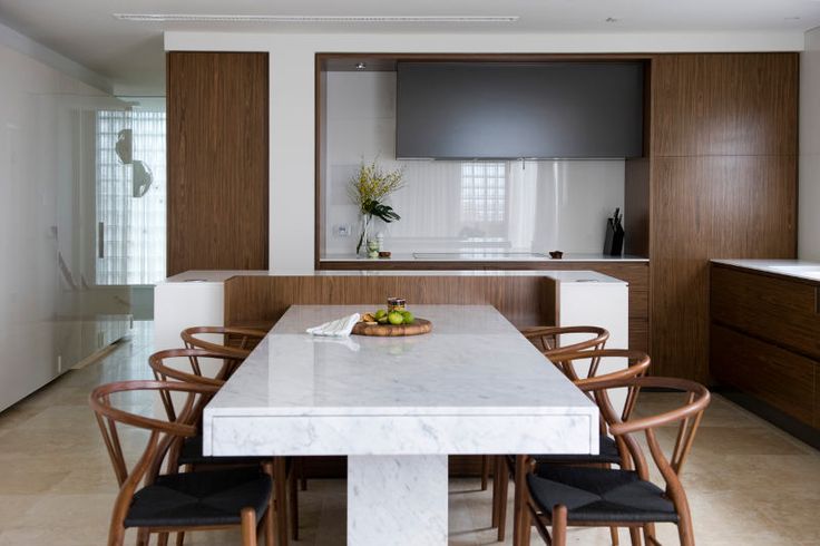 a kitchen table with chairs around it in front of a counter and cabinets behind it