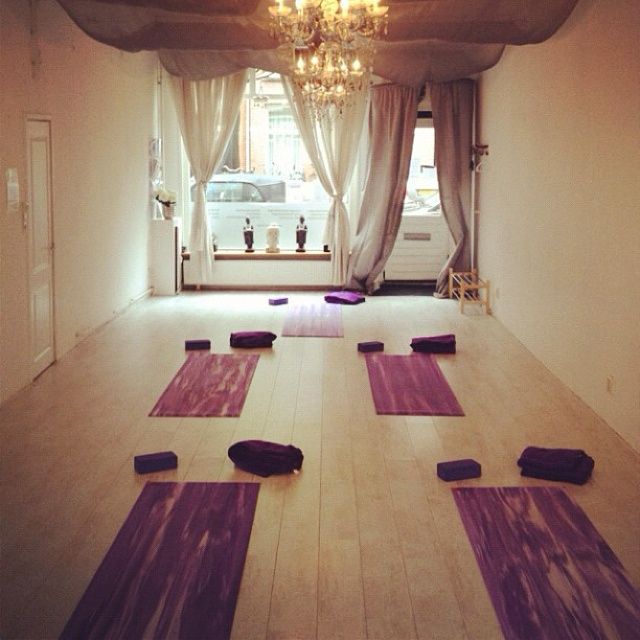 an empty room with yoga mats on the floor and a chandelier hanging from the ceiling