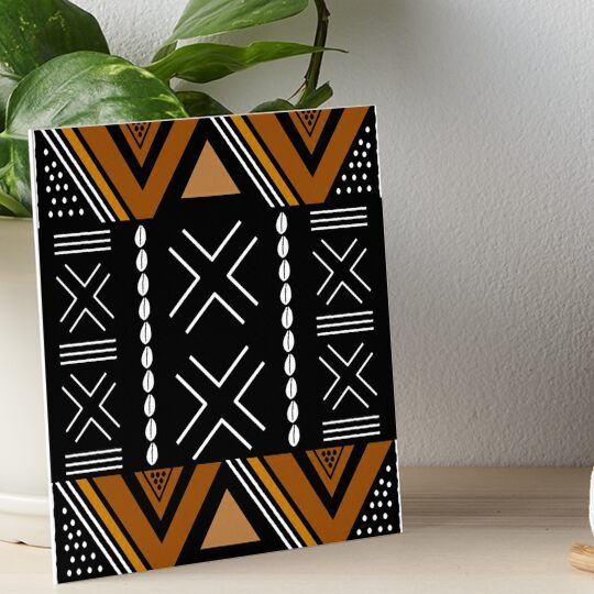 a black and orange geometric design art boarder on a table next to a potted plant