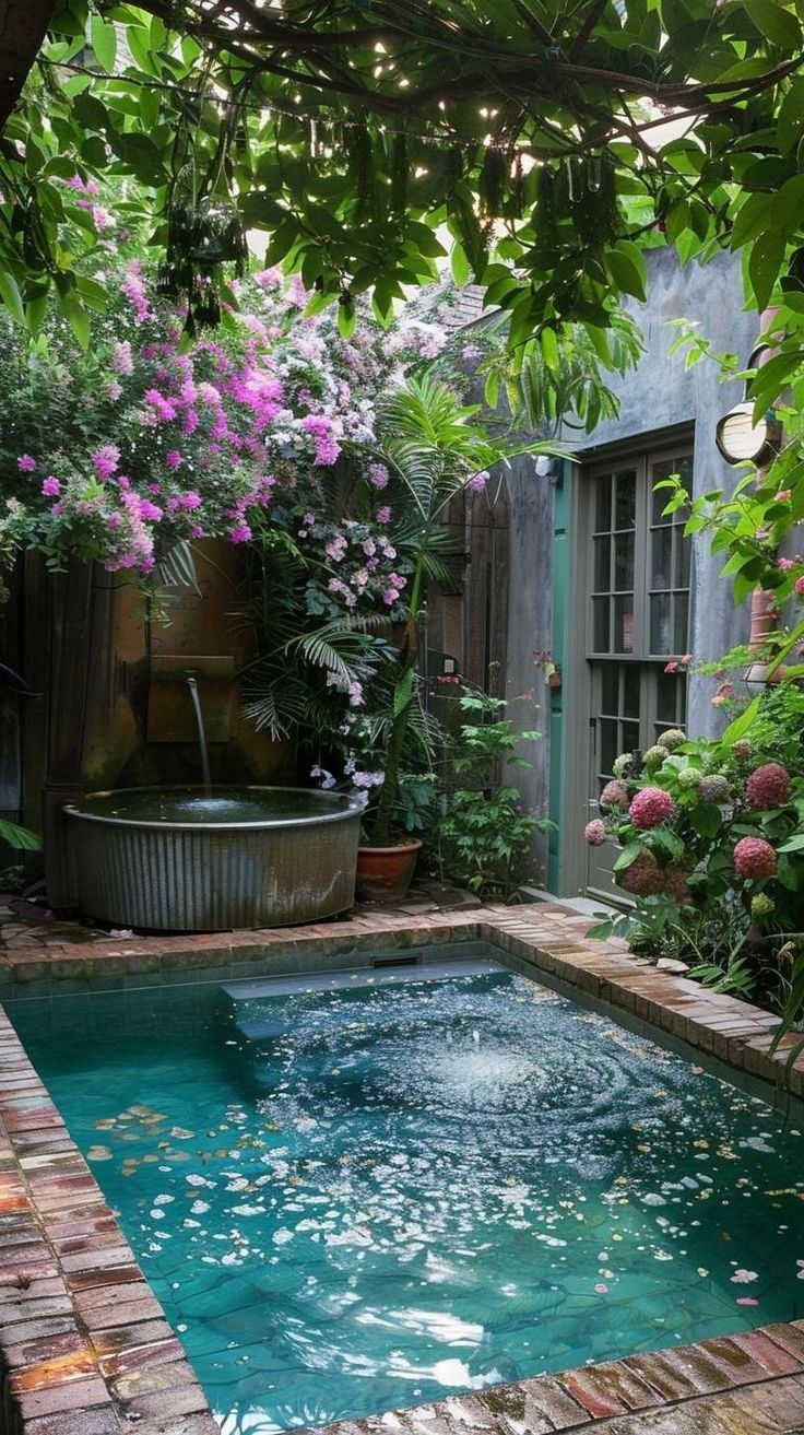 a small pool surrounded by greenery and flowers in a backyard with a hot tub