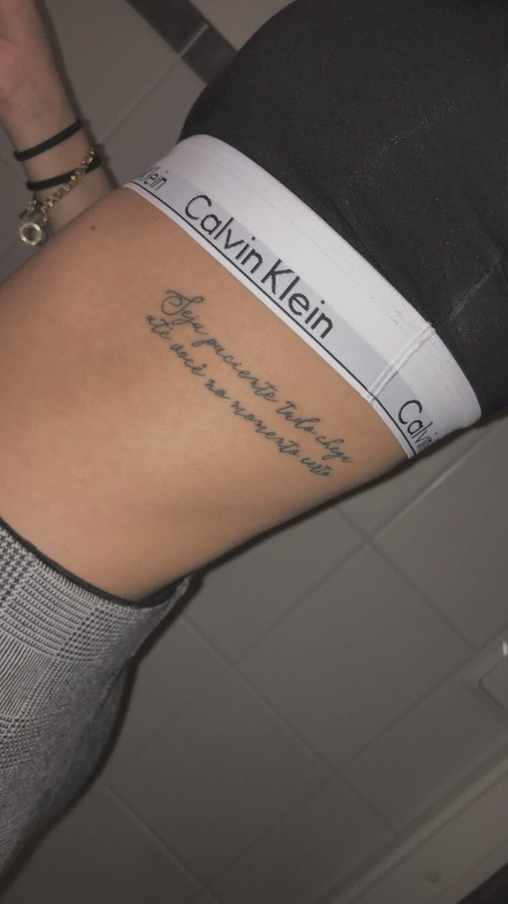 the back of a woman's lower body with tattoos on her stomach and words written in cursive writing