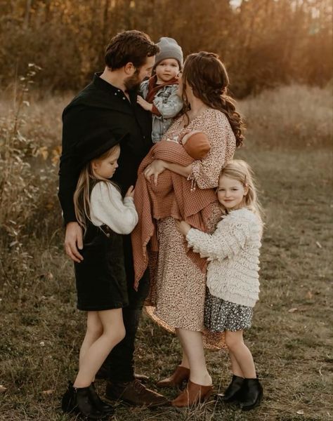 a group of people standing in the grass with one woman holding a baby and two children