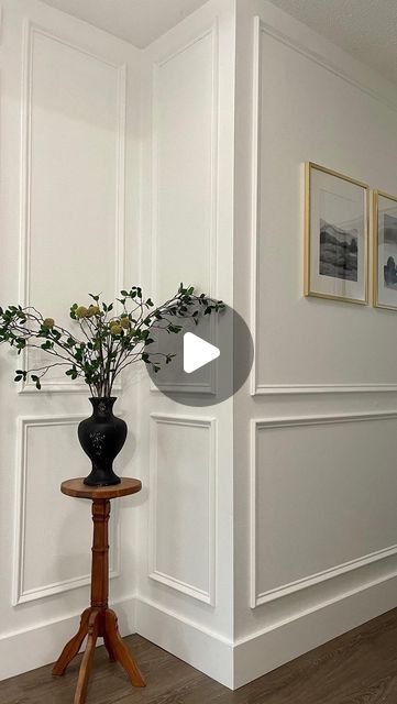 a vase with flowers sitting on top of a wooden table next to a white wall