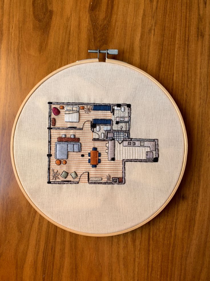 a cross - stitch embroidery project with a house in the middle and furniture on the other side