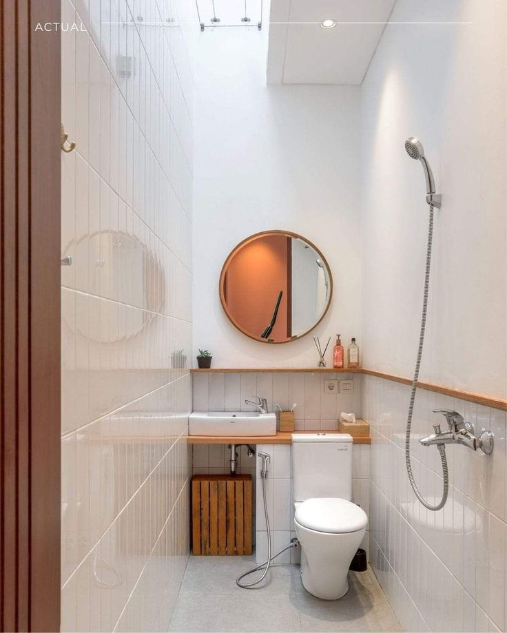 a bathroom with a toilet, sink and shower head mounted to the side of the wall