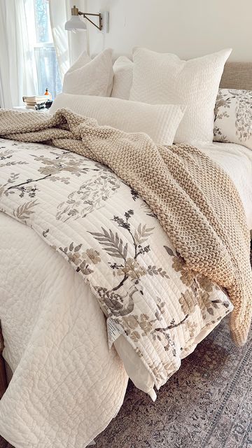 a bed with white comforter and pillows on top of it in a bedroom next to a window