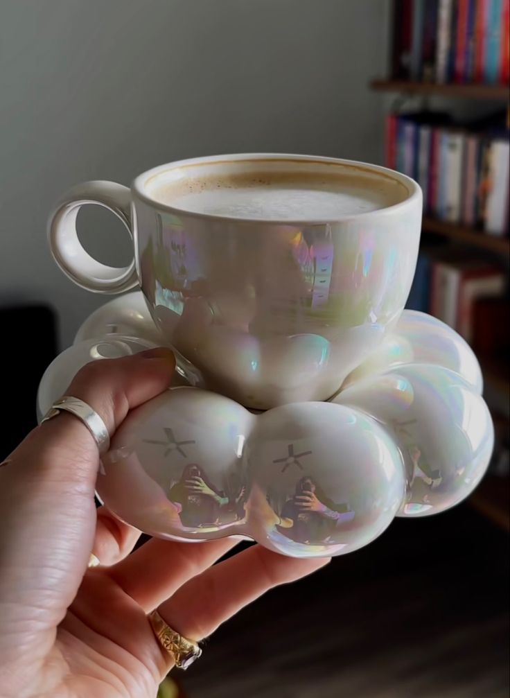 a person holding a cup of coffee in their hand with bubbles on the top and bottom