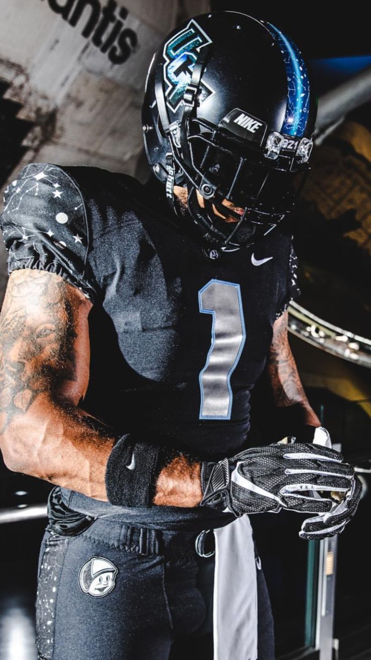 a football player wearing a black uniform and holding a ball