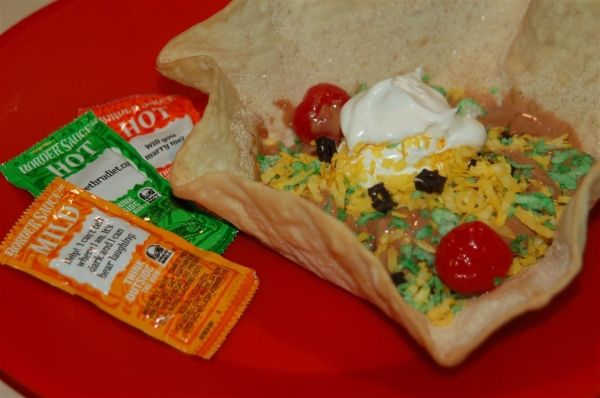 a burrito filled with cheese, tomatoes and other toppings on a red plate