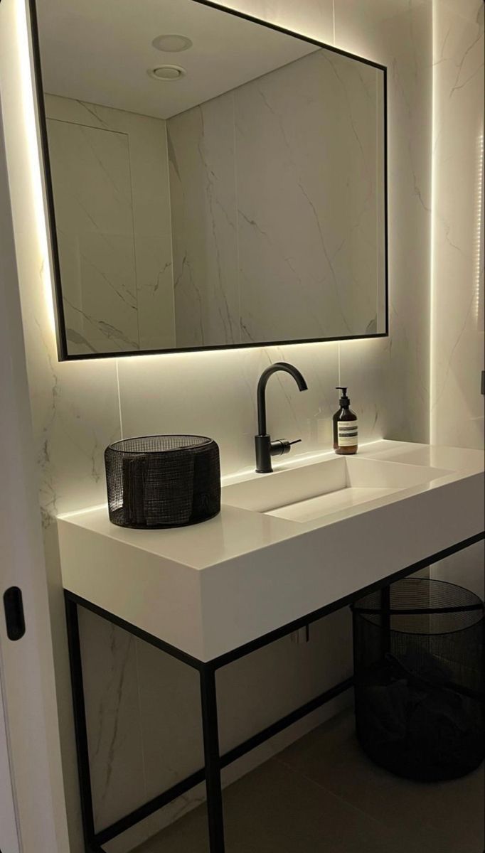 a bathroom sink with a large mirror above it and a black trash can underneath the sink