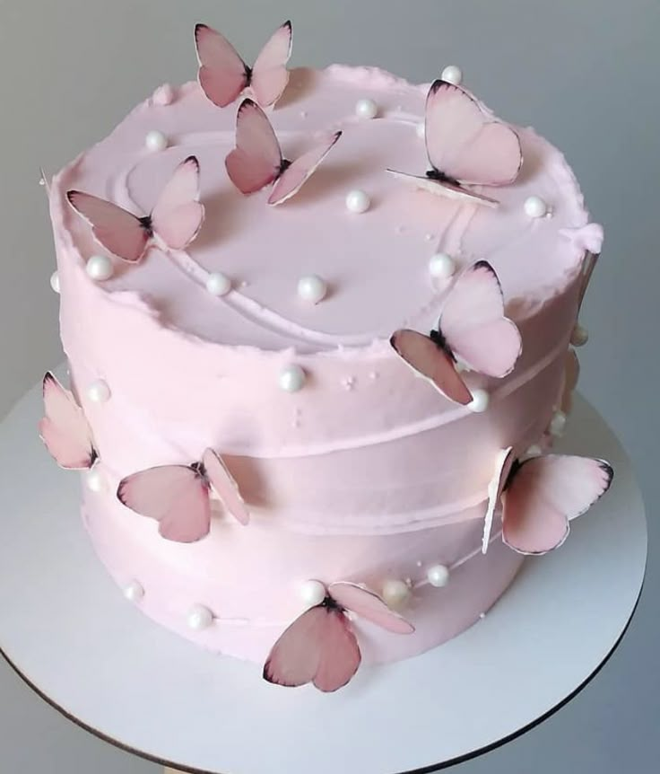 a pink cake decorated with butterflies and pearls