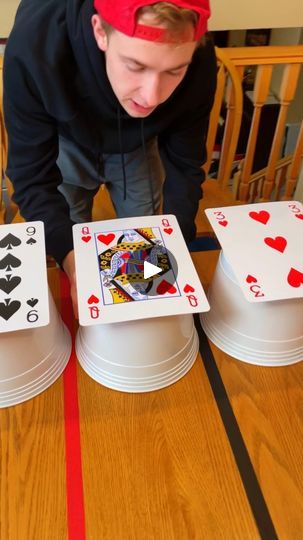 a man standing over three playing cards on top of a wooden table with red tape