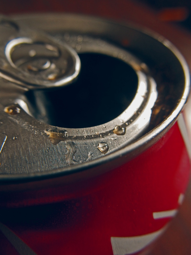 a can of soda sitting on top of a wooden table