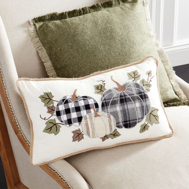 a white chair with two pillows on top of it and a plaid pumpkin pillow in the middle