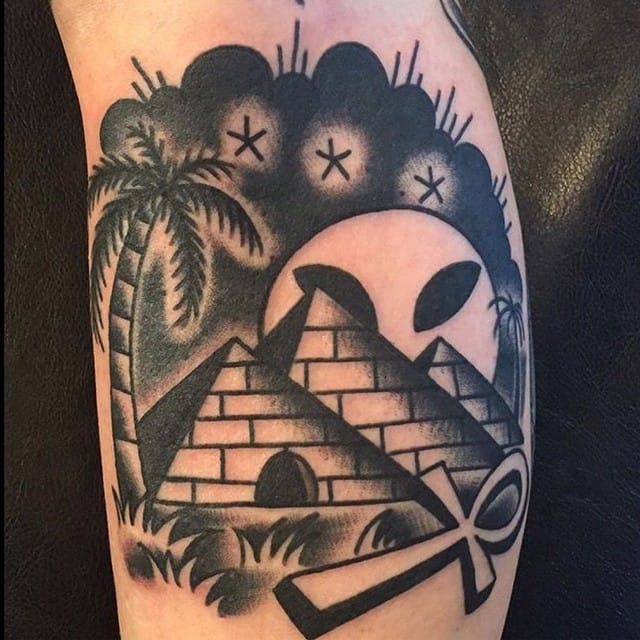 a black and white tattoo on the leg of a man's arm with an image of a pyramid