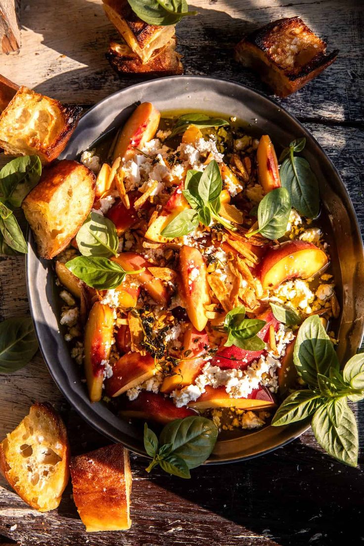 a bowl filled with food on top of a wooden table next to slices of bread