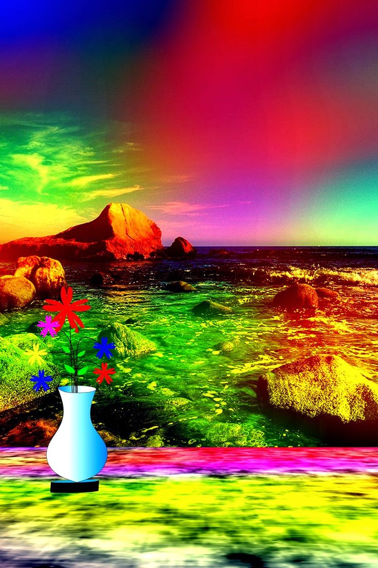 a vase filled with flowers sitting on top of a lush green field next to the ocean