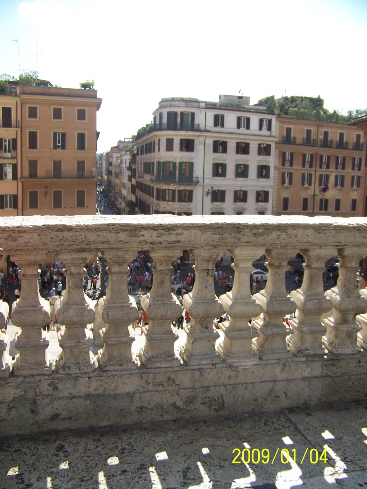 several people riding motorcycles on a bridge over looking some buildings and the sun is shining