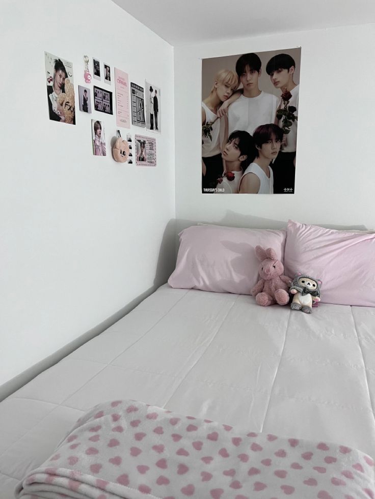 a bed with pink pillows and pictures on the wall above it, along with a teddy bear