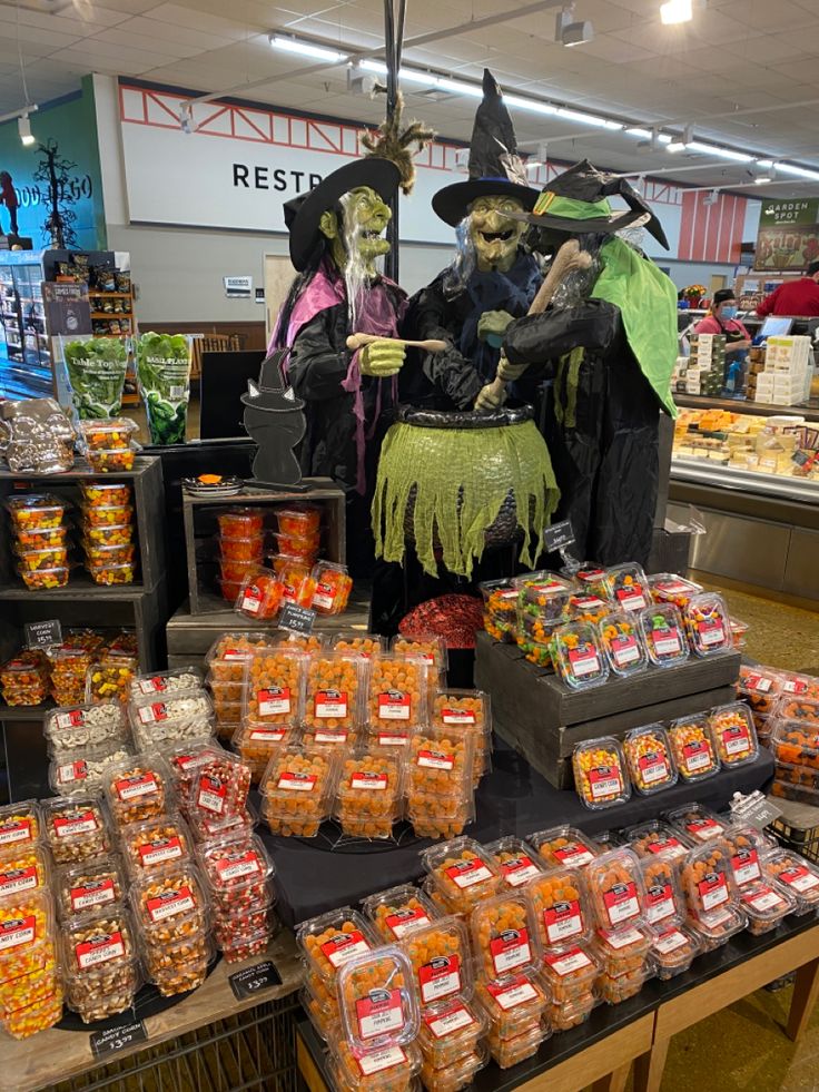 two people dressed as witches sit in front of an assortment of candy and candies