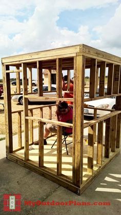 a person sitting at a table in a small wooden structure that is being built into the ground