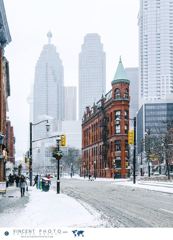 people are walking down the street in front of some tall buildings on a snowy day