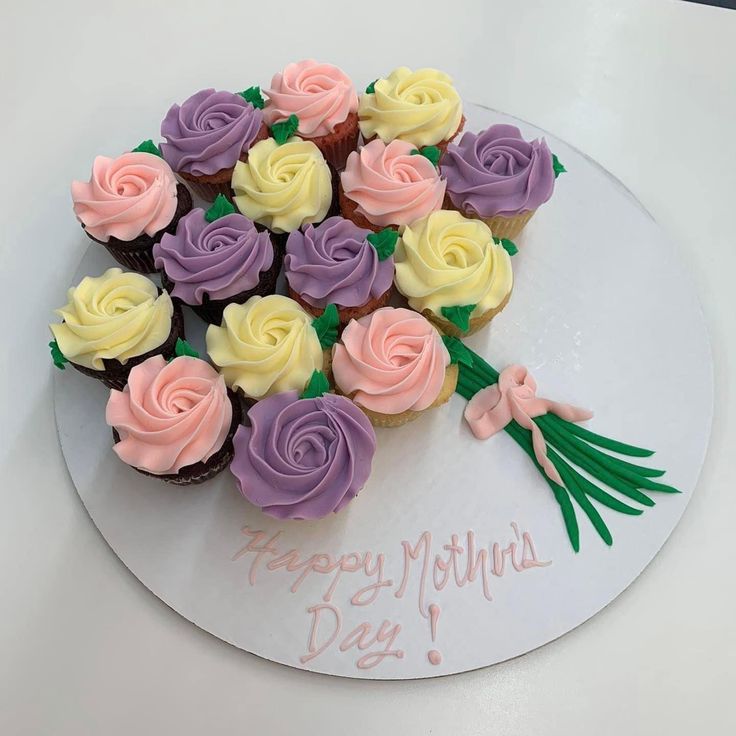 cupcakes are arranged in the shape of a heart on a white plate with pink, yellow and purple frosting