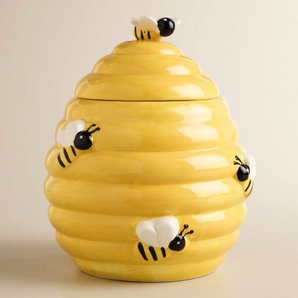 a yellow ceramic beehive with black and white bees on it's sides