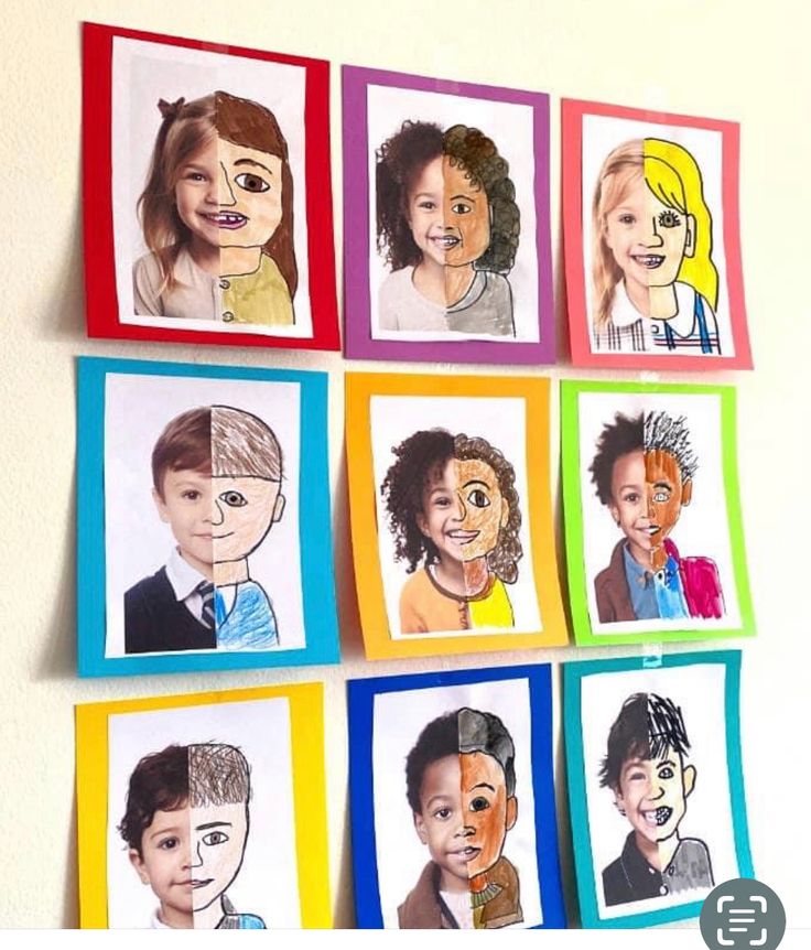 a group of children's faces are drawn on colored paper and hung on the wall