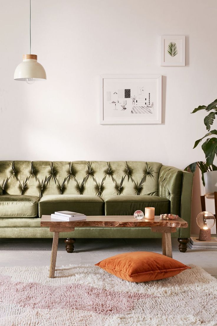 a living room with a pink couch and coffee table in front of the couch is an orange throw pillow