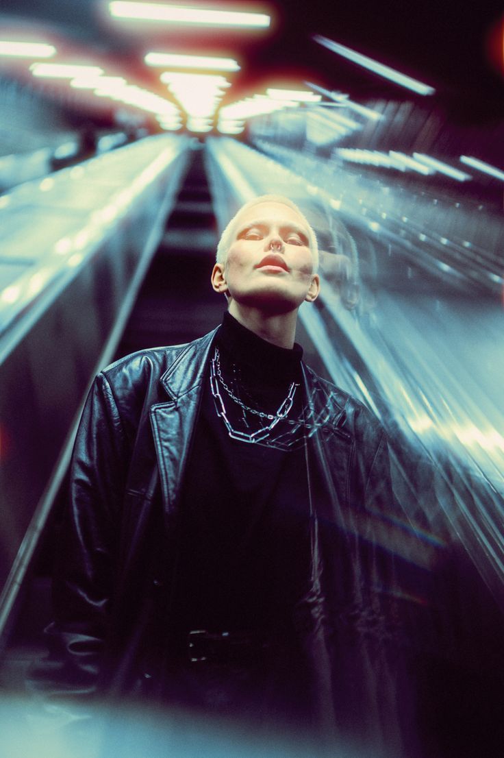 a man standing in front of an escalator with his eyes closed and head tilted to the side