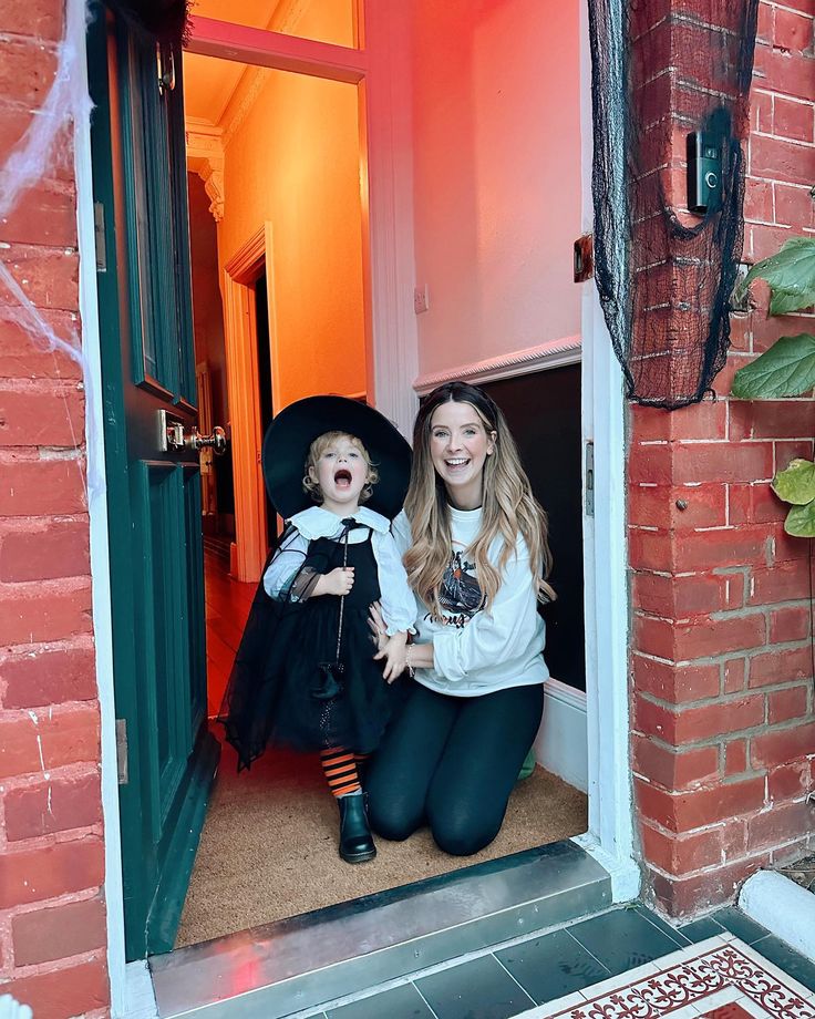 a woman holding a child in front of a door