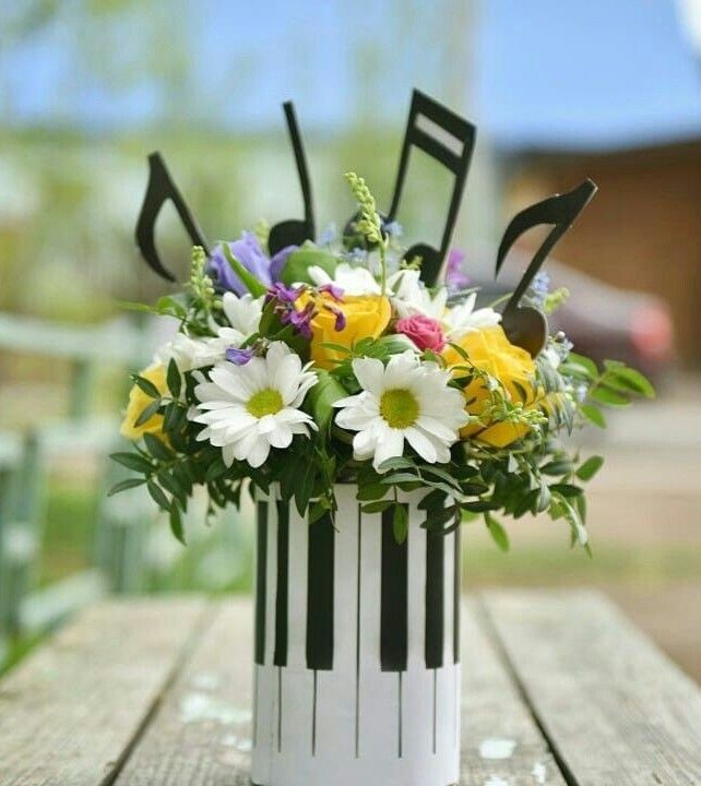 an arrangement of flowers in a white vase on a wooden table with black and white stripes