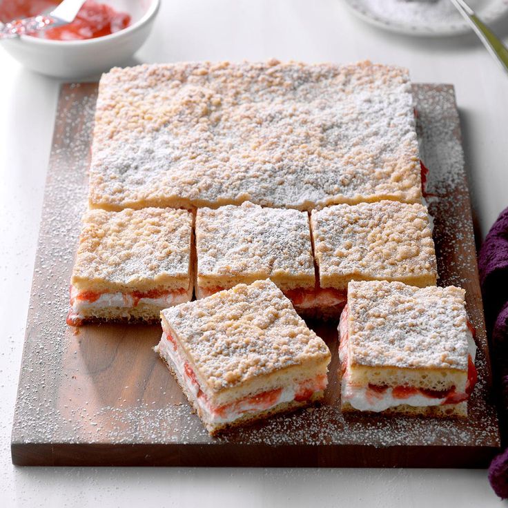 several pieces of dessert sitting on top of a wooden cutting board