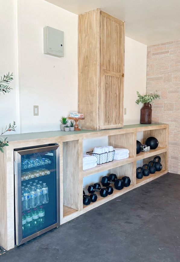 an empty room with a refrigerator and some bottles on the shelf in front of it