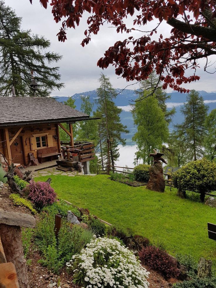 a log cabin sits on the edge of a grassy hill overlooking a body of water