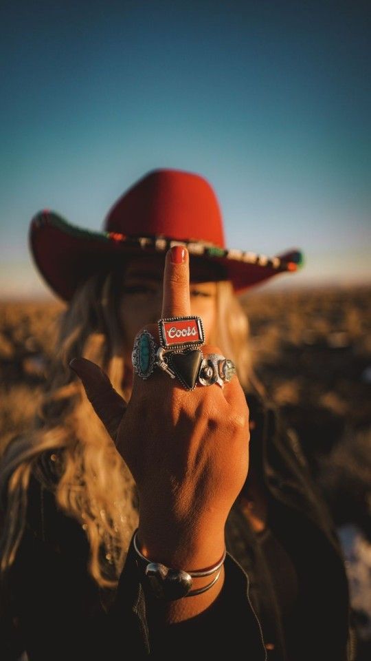 a person wearing a red hat making the peace sign with their hand and holding a camera in front of them