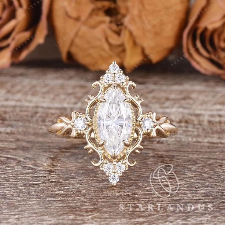 an antique style ring with a pear shaped diamond center surrounded by smaller round diamonds and gold filigrees