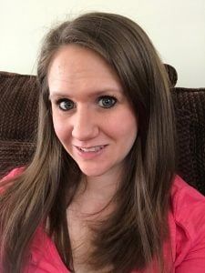 a woman with long brown hair and blue eyes is sitting on a couch looking at the camera