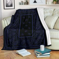 a black and blue blanket sitting on top of a wooden floor next to a white couch